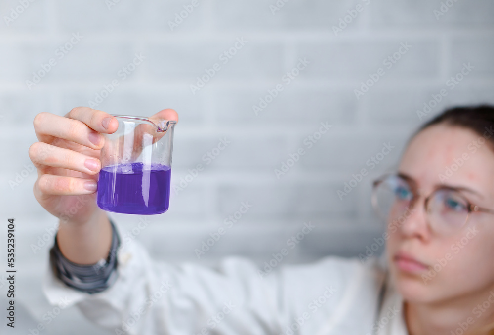 The girl examines the chemical preparation in the flask. Laboratory research. The girl examines the chemical preparation in the flask. Laboratory research.