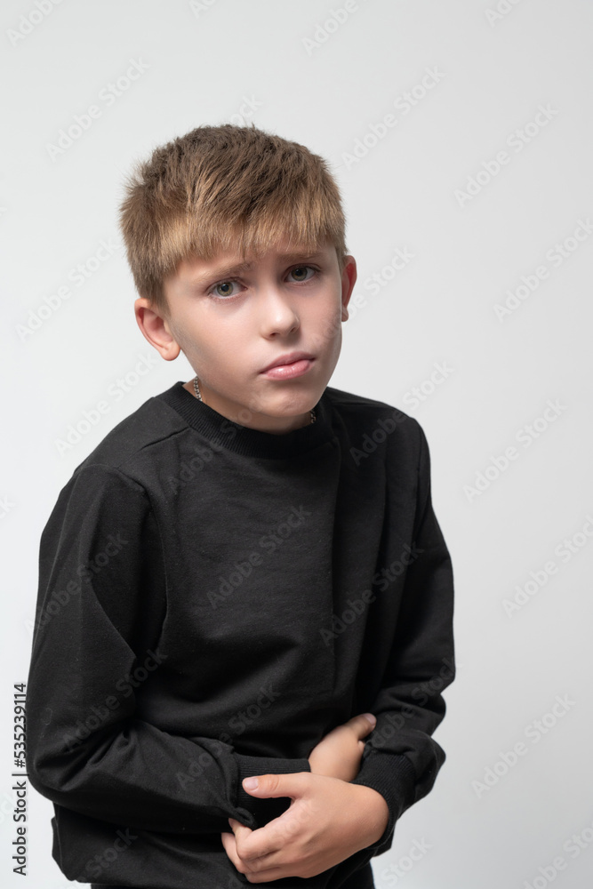 The child holds his hands to his stomach from pain. The child holds his hands to his stomach from pain.