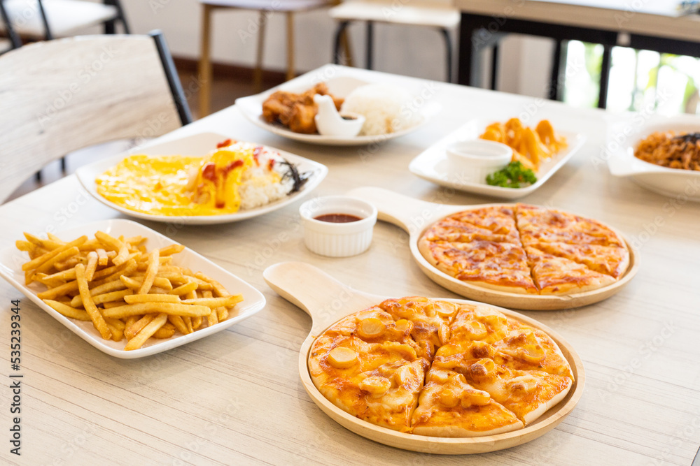 Buffet table scene of take out or delivery foods. Pizza, rice with