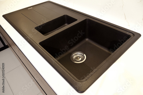 Modern and contemporary kitchen detail in luxury home, on white kitchen counter black granite sink photo