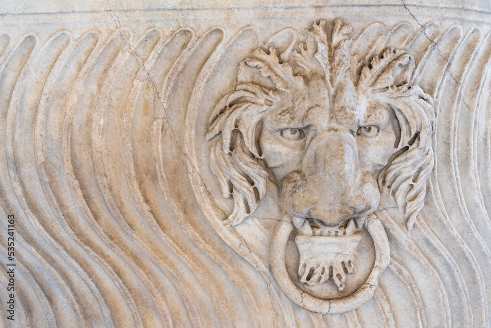 Lion head holding a knocker carved in marble wall