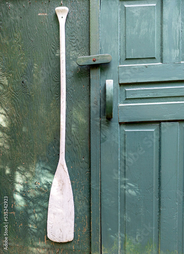 Old canoe paddle on a rustic cottage background