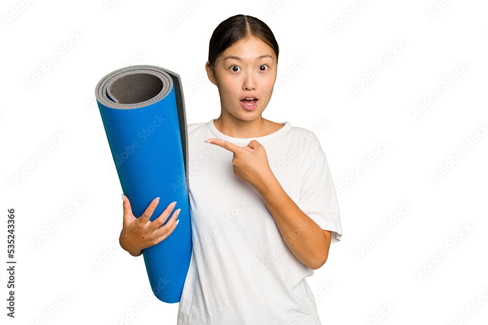 Young asian woman holding a mat isolated on green chroma background pointing to the side Young asian woman holding a mat isolated on green chroma background pointing to the side