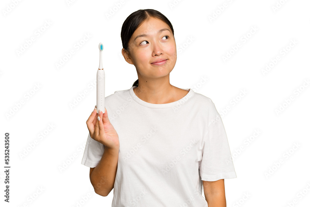 Young Asian woman holding an electric toothbrush isolated on green chroma background dreaming of achieving goals and purposes Young Asian woman holding an electric toothbrush isolated on green chroma background dreaming of achieving goals and purposes