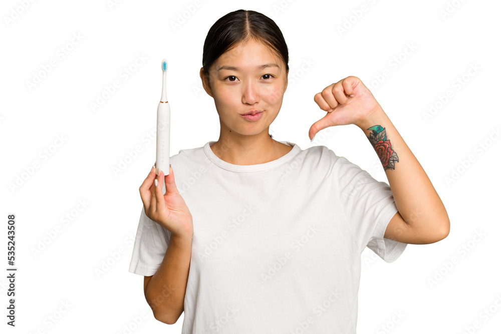 Young Asian woman holding an electric toothbrush isolated on green chroma background feels proud and self confident, example to follow. Young Asian woman holding an electric toothbrush isolated on green chroma background feels proud and self confident, example to follow.
