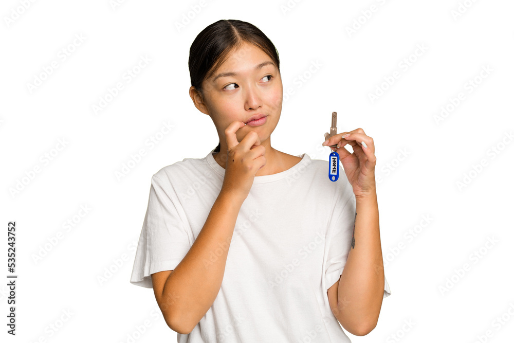Young asian woman holding home keys isolated on green chroma background relaxed thinking about something looking at a copy space. Young asian woman holding home keys isolated on green chroma background relaxed thinking about something looking at a copy space.