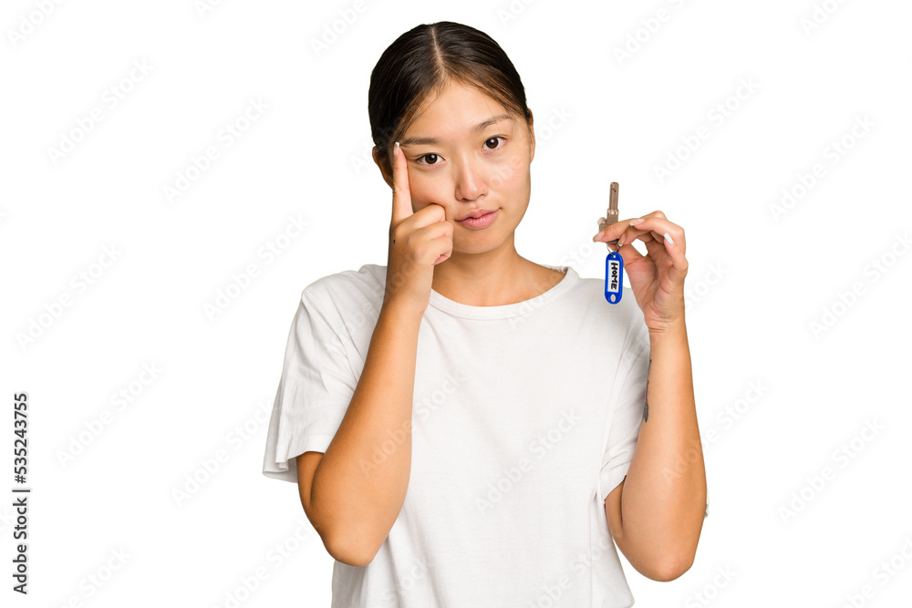 Young asian woman holding home keys isolated on green chroma background pointing temple with finger, thinking, focused on a task. Young asian woman holding home keys isolated on green chroma background pointing temple with finger, thinking, focused on a task.