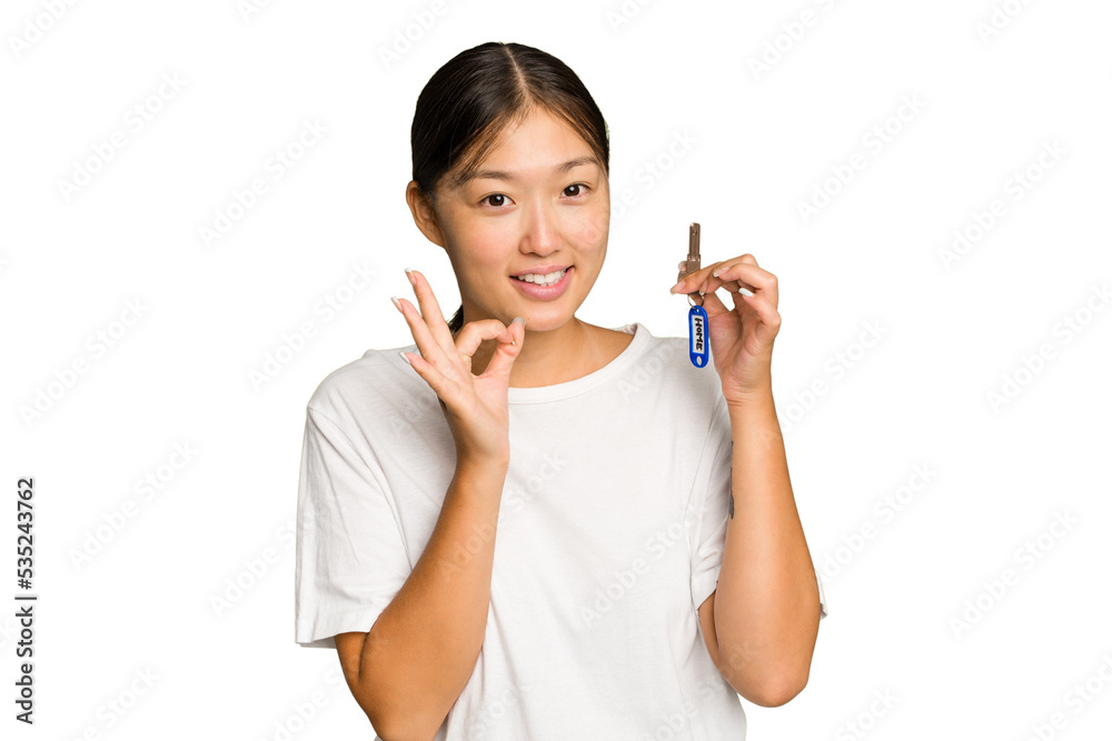 Young asian woman holding home keys isolated on green chroma background cheerful and confident showing ok gesture. Young asian woman holding home keys isolated on green chroma background cheerful and confident showing ok gesture.