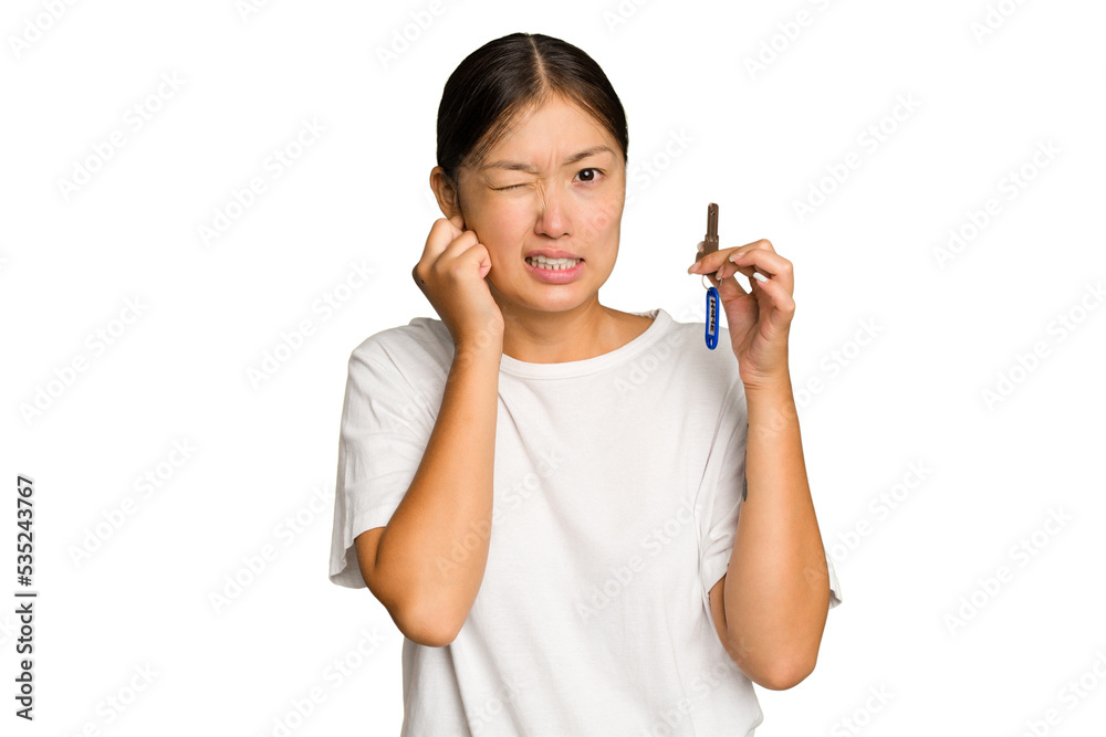 Young asian woman holding home keys isolated on green chroma background covering ears with hands. Young asian woman holding home keys isolated on green chroma background covering ears with hands.