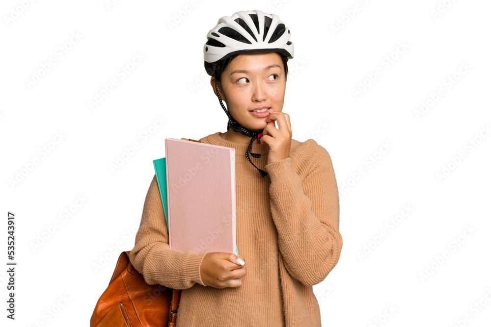 Young student asian woman wearing a bike helmet isolated on green chroma background relaxed thinking about something looking at a copy space. Young student asian woman wearing a bike helmet isolated on green chroma background relaxed thinking about something looking at a copy space.