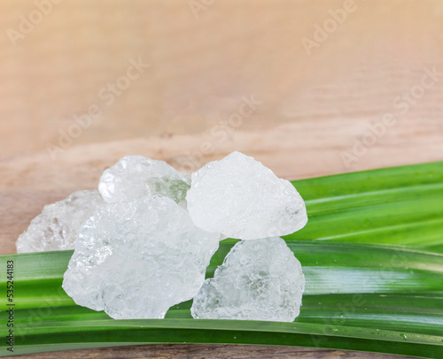 Crystal clear alum cubes or Potassium alum on green leaf. Chemical compound substance. Concept for beauty, spa and underarm treatment industrial.                                                       photo