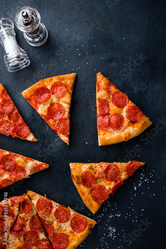 Tasty pepperoni pizza on black concrete background. Top view of hot pepperoni pizza. With copy space for text. Flat lay. Banner
