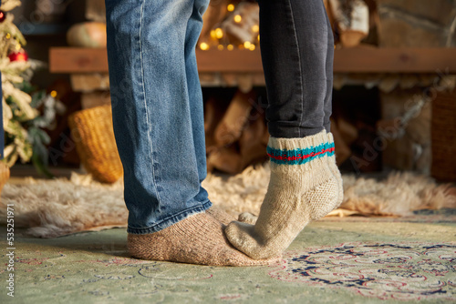 man and woman legs in woolen socks against the background of a fireplace. Home comfort and warmth. Christmas and New Year. Winter and autumn season