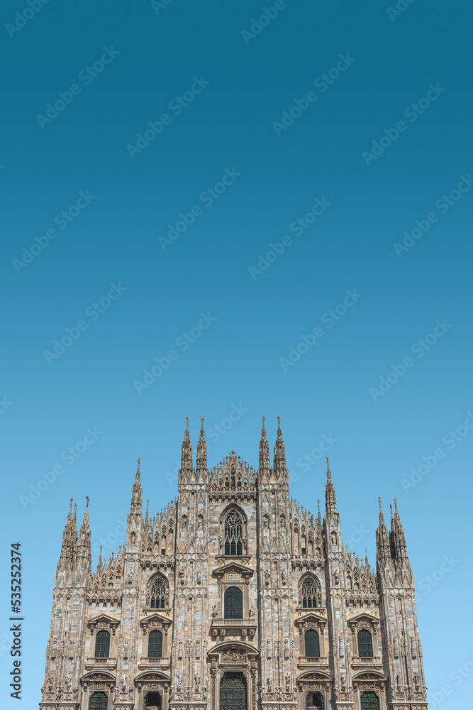 Cover page with magnificent Cathedral of Milano, Duomo di Milano, at blue sky gradient background with copy space, Milan, Italy. Concept of historical and religious heritage sites conservation.