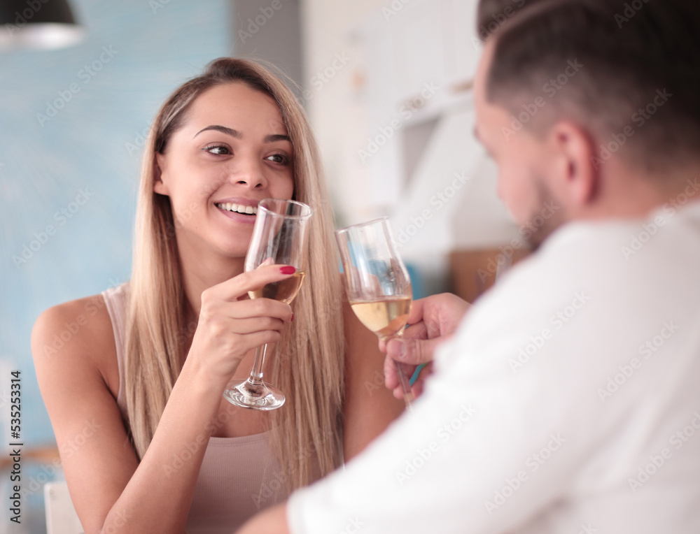 young couple with glasses of wine sitting in the kitchen young couple with glasses of wine sitting in the kitchen