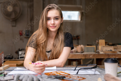 Portrait of a female carpenter drawing on paper for designing and building furniture in a furniture factory. with modern tools
