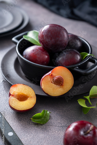 Fresh cherry plum fruits in black bowl, dark and moody food photo