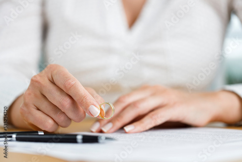 Hands of female who is about to taking off her wedding ring. Divorce concept photo