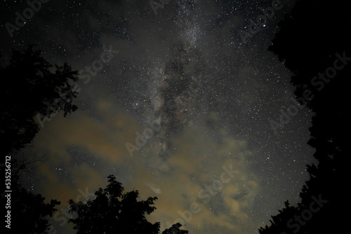 A look up into the dark night sky with passing clouds reflecting the light dome pollution from nearby cities, masking a view of the galactic center of the Milky Way galaxy