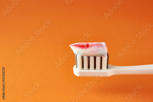 Toothbrush with toothpaste on an orange background. Dental care. Oral hygiene.