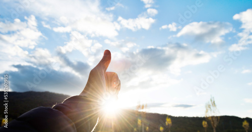 thumb up against the sunny sky