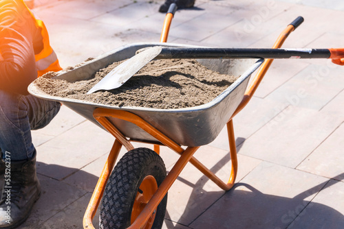 Fotografia construction wheelbarrow with sand and shovel