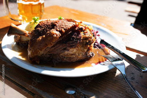 Crusty knuckle of pork in a beer garden.Traditional oktoberfest food with ingredients and fresh beer.