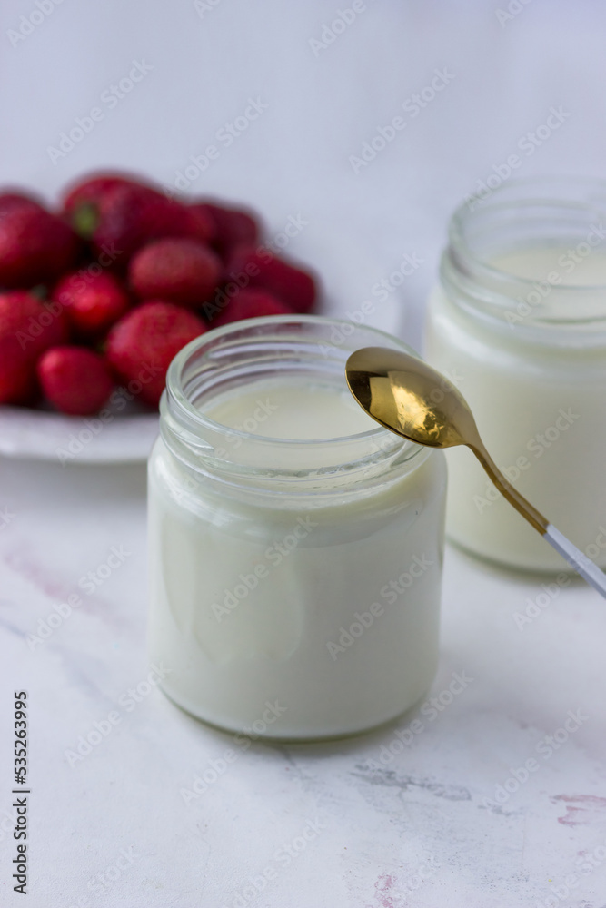 Homemade yogurt. Jars of yogurt and strawberries on a white table. Proper nutrition Homemade yogurt. Jars of yogurt and strawberries on a white table. Proper nutrition
