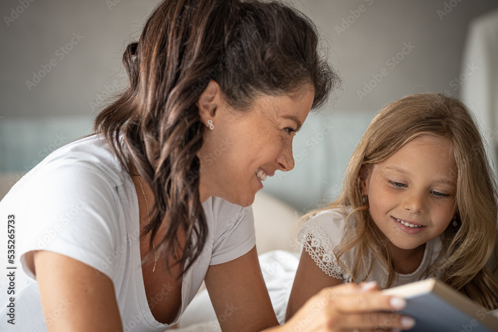 Mother and daughter reading book together on bed in bedroom
Having fun together, smiling Mother and daughter reading book together on bed in bedroom
Having fun together, smiling
