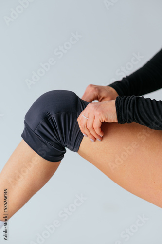 Female dancer wears a protective knee brace before training. Vertical.