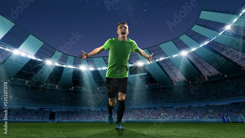 Winner emotions. Excited soccer player running at the crowded stadium with spot lights during evening football match. Concept of sport, competition, championship