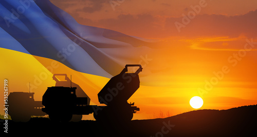 Artillery rocket system are aimed to the sky at sunset with Ukrainian flag. Multiple launch rocket system. 3d-rendering. © hamara