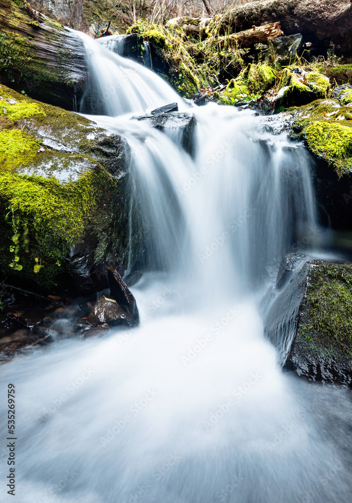 Obraz premium Blurred waterfall throughing mossy rocks