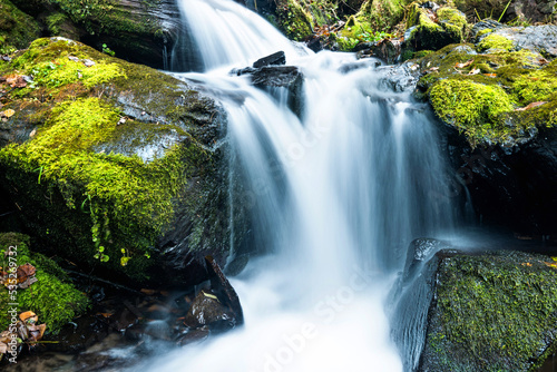 Blurred waterfall throughing mossy rocks