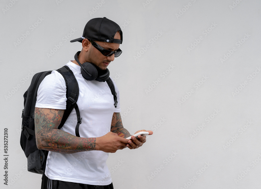 A tattooed male tourist is searching for information with a smartphone. A tattooed male tourist is searching for information with a smartphone.