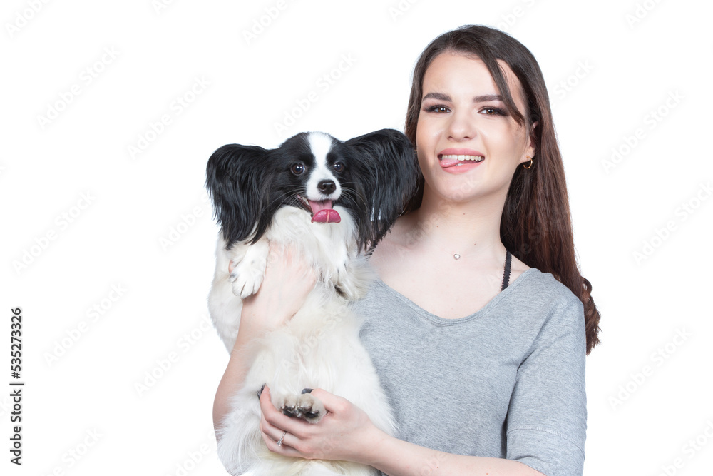 A cute young woman is hugging her papillon puppy. Love between owner and dog. Girl with dog studio portrait. A cute young woman is hugging her papillon puppy. Love between owner and dog. Girl with dog studio portrait.