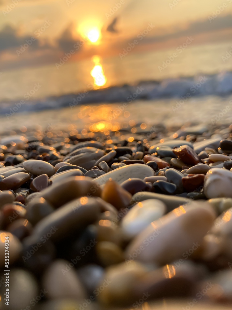 Obraz premium View of the sea and sun rising above the stones in Cirali, Antalya, Turkey. Selective focus.