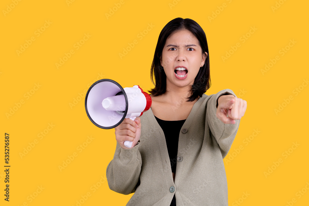 Friendly young woman holds a megaphone in her hands and points her finger at the viewer on a yellow background. Hiring concept, help wanted. Banner. Friendly young woman holds a megaphone in her hands and points her finger at the viewer on a yellow background. Hiring concept, help wanted. Banner.