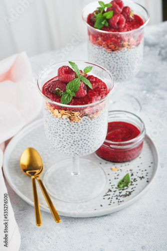 Chia pudding. Healthy vanilla chia pudding in glass with fresh raspberries and mint on white background. Vegan healthy breakfast.