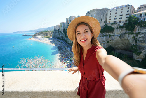 Selfie girl in Tropea, Italy. Young tourist woman taking self portrait with Tropea village on Coast of the Gods, Calabria, Italy. photo