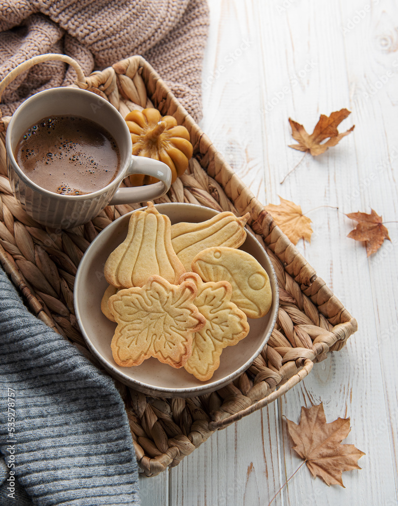 Cup of coffee, cookies on tray, yellow leaves.