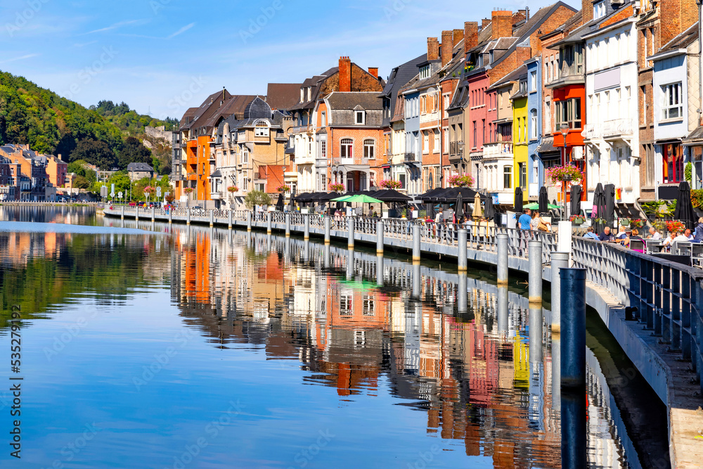 Dinant, Belgium. View on street with typical traditional colorful houses on the river Meuse against blue sky