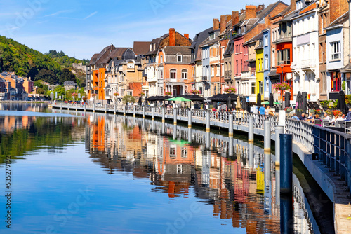 Dinant, Belgium. View on street with typical traditional colorful houses on the river Meuse against blue sky