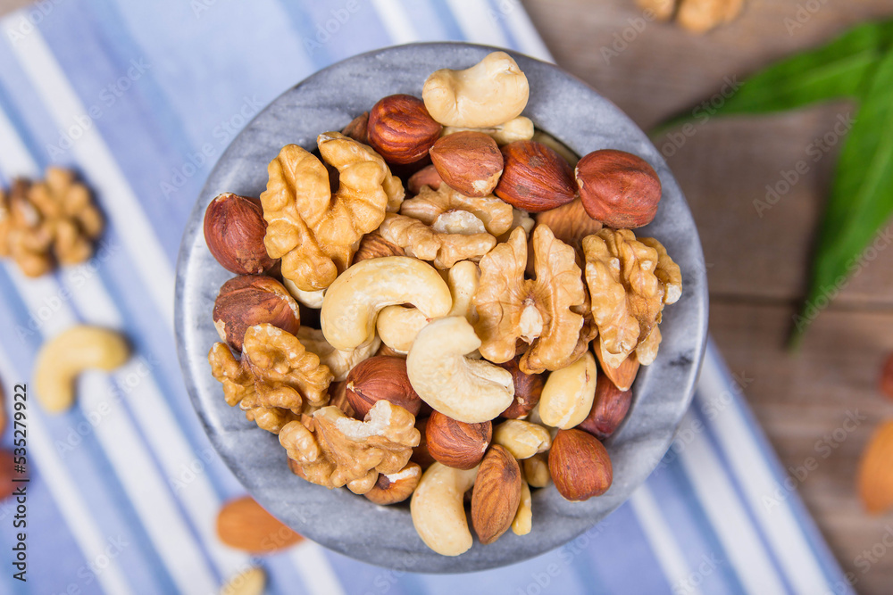 Obraz premium Marble bowl filled with shelled almonds, walnuts, cashew nuts