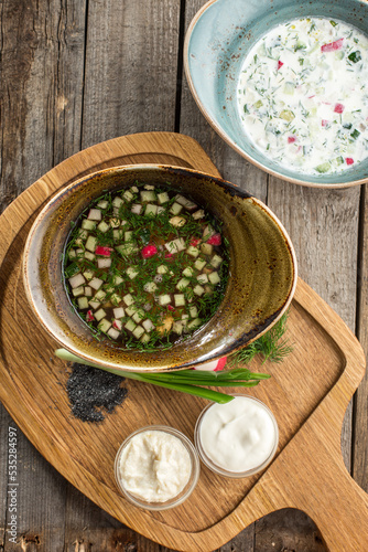 Okroshka traditional Russian cold soup with fresh cucumber, boiled eggs and dill on the table
