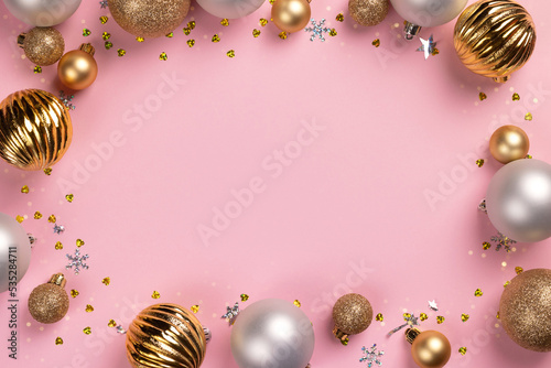 Christmas card frame with golden and silver balls and confetti on pink background with copy space