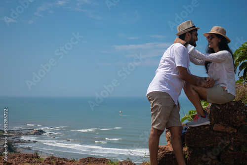 Beautiful young lovely attractive tourist couple looking each other, embracing, making love, smiling, cuddling enjoying their time with a beautiful view of Chapora fort in Goa. Baga, Candolim, Vagator photo