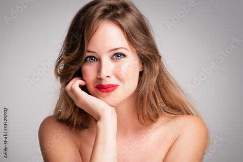 Beauty shot of gorgeous woman wearing red lipstick while standing at isolated grey background
