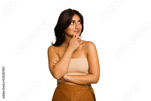 Young Indian woman isolated on green chroma background looking sideways with doubtful and skeptical expression.