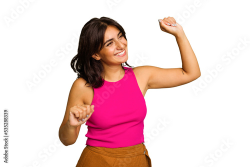 Young Indian woman isolated on green chroma background celebrating a special day, jumps and raise arms with energy.
